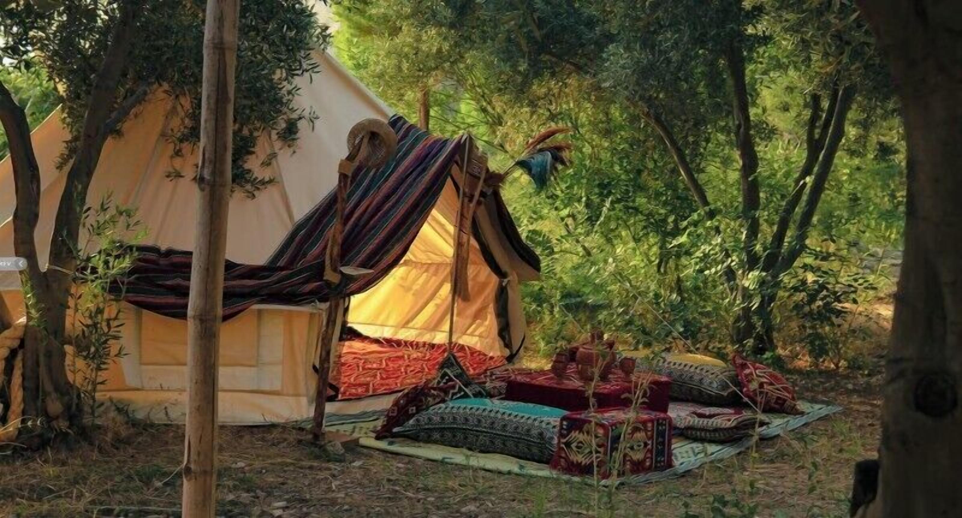 A tent with a colorful striped canopy, surrounded by trees and a forested area.