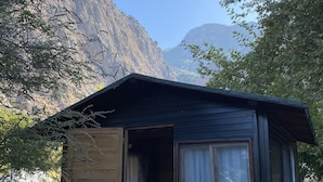 A small wooden cabin with a bed inside, a window, and a door. - Kelebekler Vadisi Butterfly Valley (Fethiye)