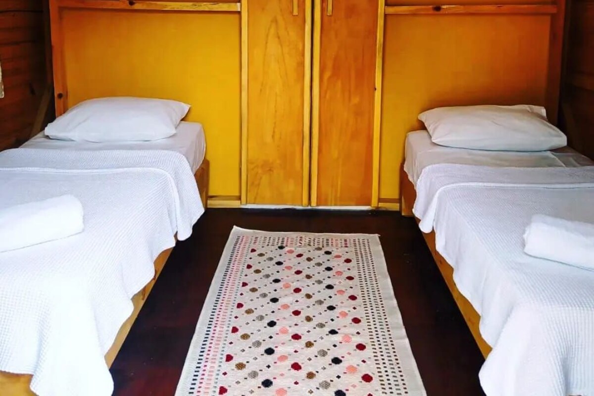 A room with two single beds, wooden walls, and a central wooden panel.