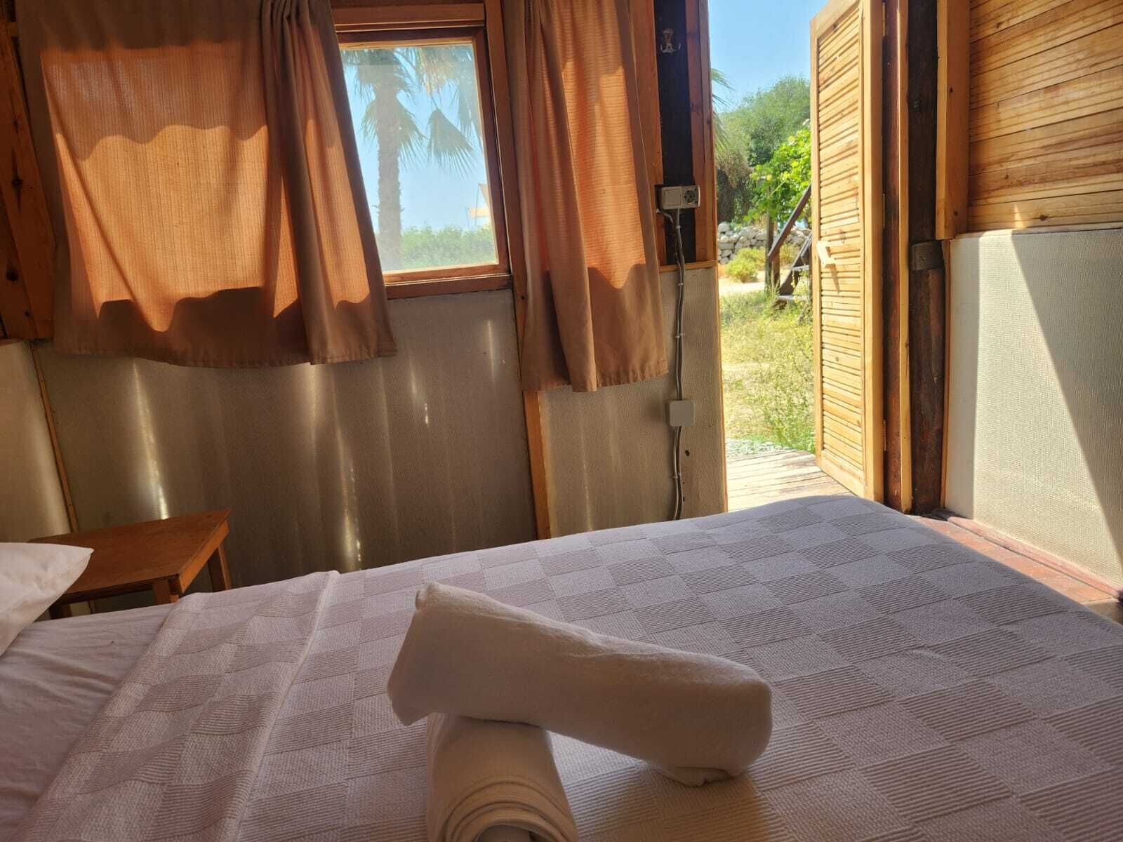 A room with a bed, a small table, and a window with curtains.