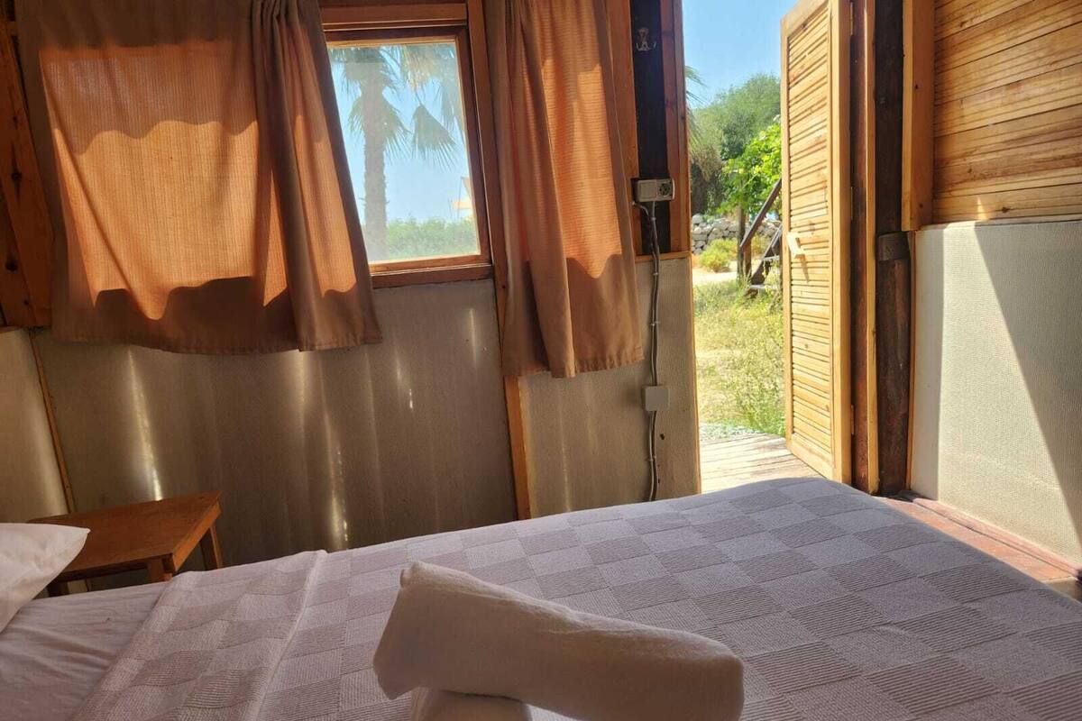 A room with a bed, a small table, and a window with curtains.