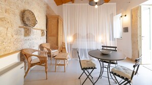 Un'accogliente zona pranzo con sedie in vimini, un tavolo rotondo e un mobiletto in legno.