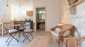 Una cucina moderna con zona pranzo, parete in pietra, mobili in vimini e un piccolo tavolo.