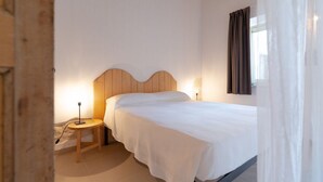 Una camera da letto con una testiera in legno, un letto singolo, un comodino con una lampada e una finestra con tende.