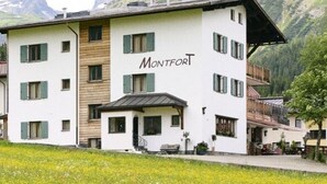 A hotel with a white facade, balconies, and a sign that reads "Montfort". - Montfort (Lech am Arlberg)