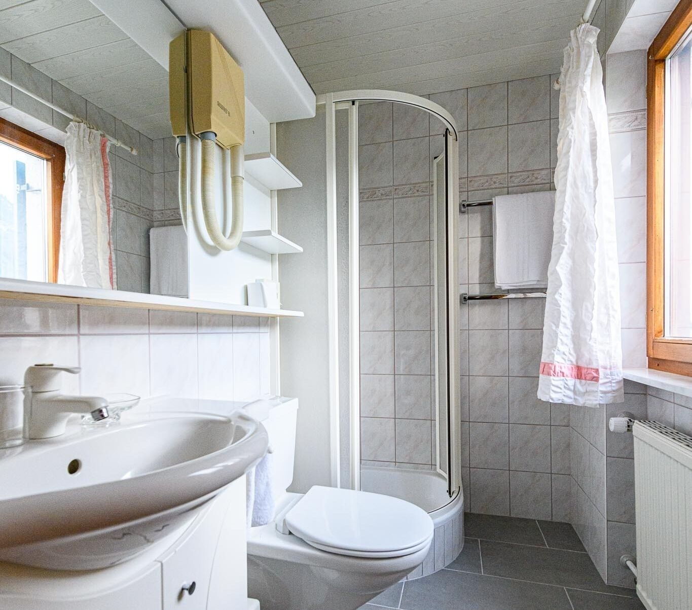 A compact bathroom with a toilet, sink, and shower.