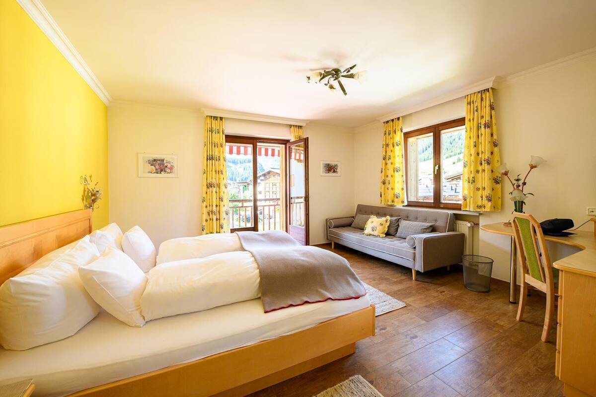A bedroom with a bed, a sofa, a desk, and a chair.