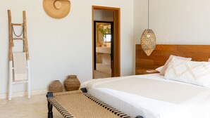 A bedroom with a wooden headboard, a bed with white bedding, a woven mat, a ladder, and a straw hat on the wall. - Casa Delfín by Luxe Haus™  – Butlered Villa, Staff, Pool, Golf Carts (La Romana)