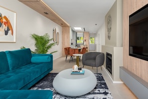 A modern living room with a teal sofa, a round coffee table, and a fireplace. - Luxe Oasis on Trendy Loader St | Pool | Ocean View (Cape Town)