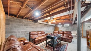 A cozy living room with leather sofas, a foosball table, and a brick wall. - Countryside- 3 Bedroom Home (Mantua)