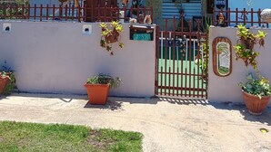 Ein zweistöckiges Haus mit Balkon, geschlossenem Eingangsbereich und Kübelpflanzen.