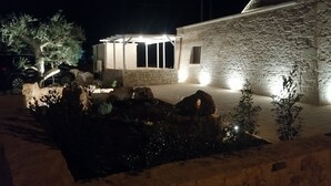 A stone building with a covered outdoor area, a stone wall, and a small water feature. - Trullo manivida Mulberry (Locorotondo)