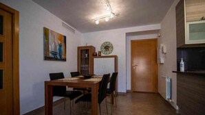 A dining area with a wooden table and chairs, a painting on the wall, a cabinet, and a clock. - Uncle Pepe House (Valderrobres)