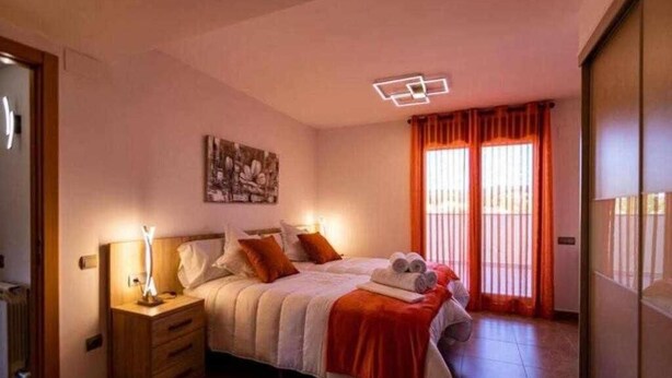 A bedroom with a bed, nightstand, and a painting on the wall. - Uncle Pepe House (Valderrobres)