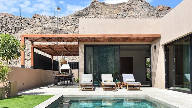 Un área de piscina moderna con una vista despejada de las montañas al fondo.
