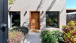Una casa moderna con puerta de madera, ventanas amplias y un camino de hormigón que lleva a la entrada.
