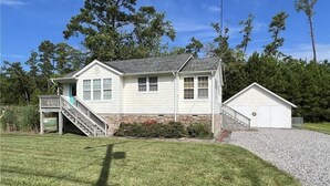 A two-story house with a front porch, a small attached garage, and a stone foundation.