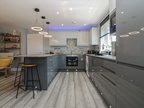 Une cuisine moderne dotée d’un îlot central, d’appareils électroménagers en acier inoxydable et d’un pare-feu décoratif.