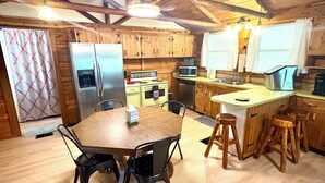 A rustic kitchen with wooden beams, a central island with stools, and modern appliances. - 22 miles to Round Top, 3/2 w/ trailer parking, relaxing cozy cabin w/ lake, wifi (La Grange)