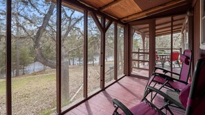 A covered porch with large windows overlooking a natural landscape and a body of water. - 22 miles to Round Top, 3/2 w/ trailer parking, relaxing cozy cabin w/ lake, wifi (La Grange)