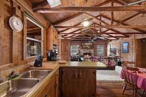 Cozy cabin-style interior with a central kitchen, dining area, and fireplace.