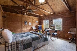 Cozy cabin-style room with a bed, desk, and window offering a view.