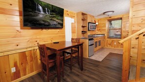 Un intérieur en bois comprenant un coin repas, une cuisine et un téléviseur fixé au mur.