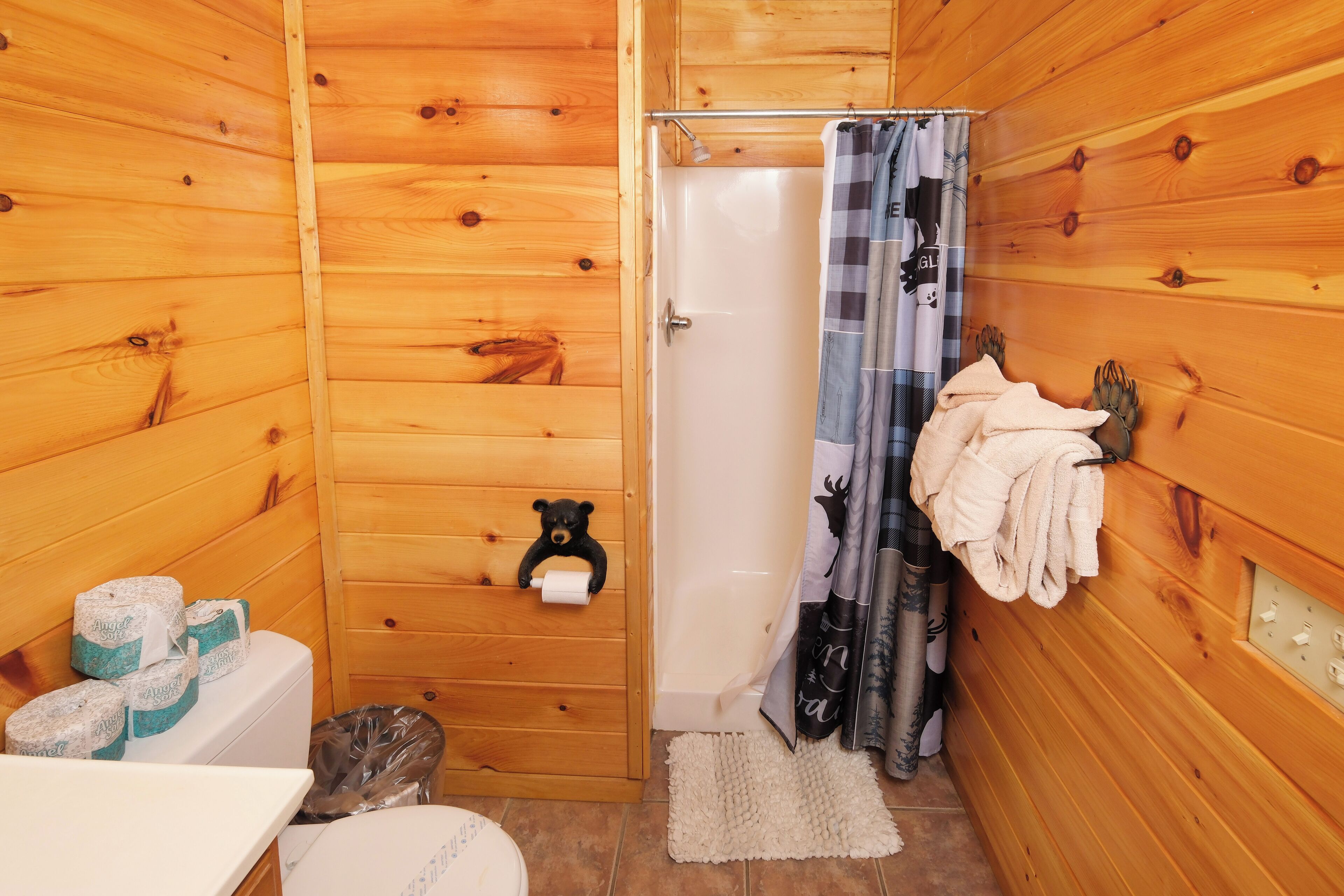 A wooden cabin bathroom with a toilet, a towel rack, and a shower curtain.