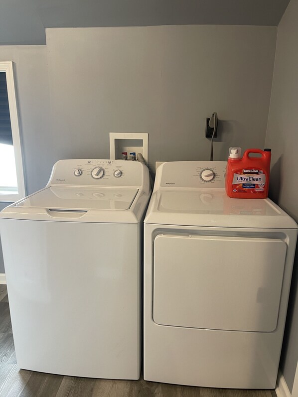 Two white front-loading washing machines in a laundry room with a gray wall and a door to the left. - Chic & Modern Stay walking distance to restaurants, bars and shops! (Louisville)