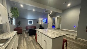 Una cocina moderna con armarios blancos, encimera de mármol y taburetes rojos.
