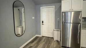 Una cocina con paredes grises, un refrigerador de acero inoxidable y una puerta blanca.