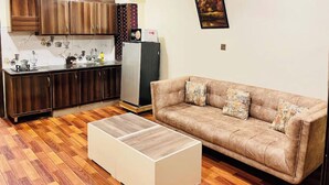A compact living space with a kitchenette, a sofa, and a coffee table. - Comfy apartment in Bahria town civic center. (Rawalpindi)