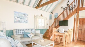 A cozy living room with a wooden staircase, a sofa set, and a dining table. - Dovecote (St Austell)