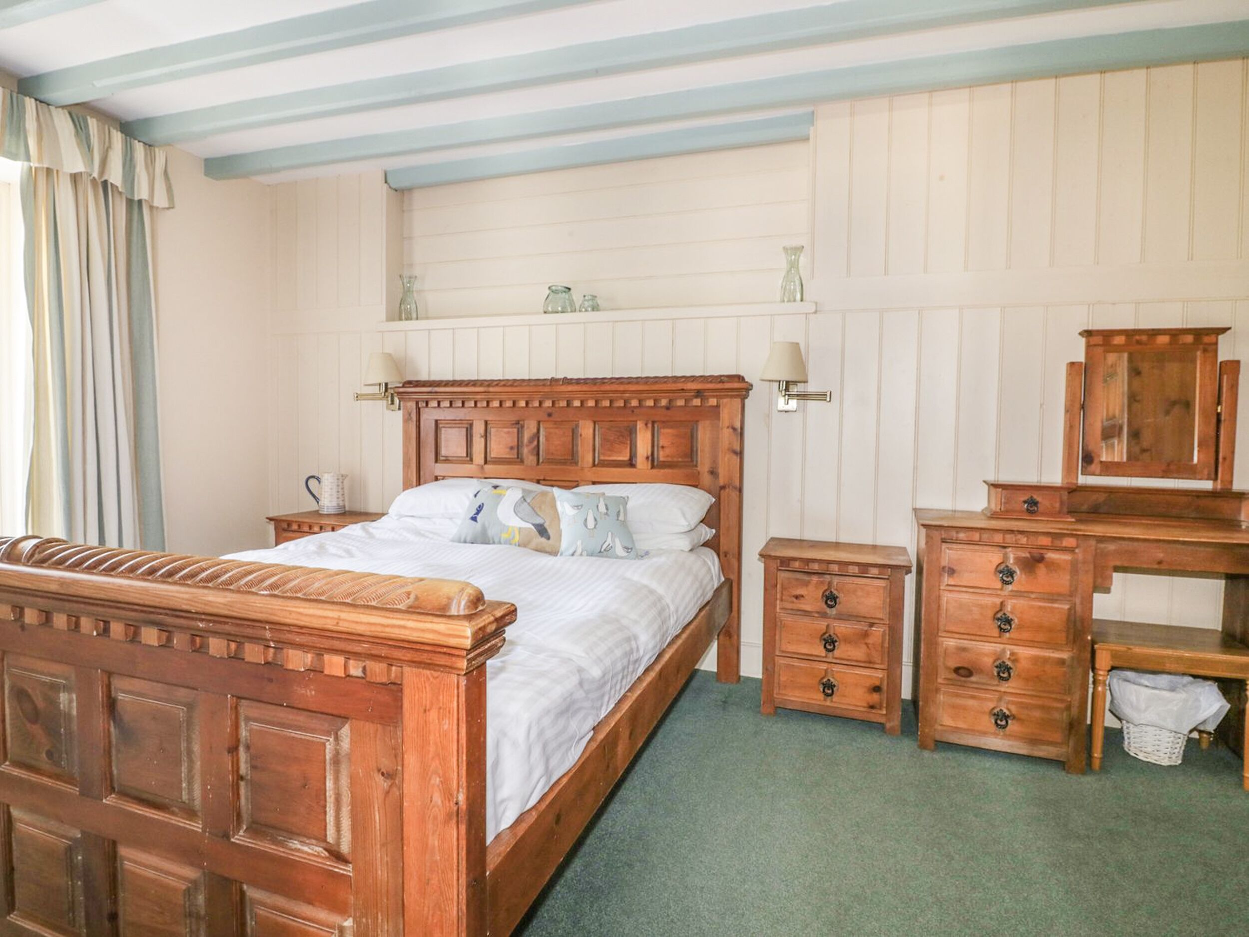 A bedroom with a wooden bed, a dresser, a mirror, and a nightstand.
