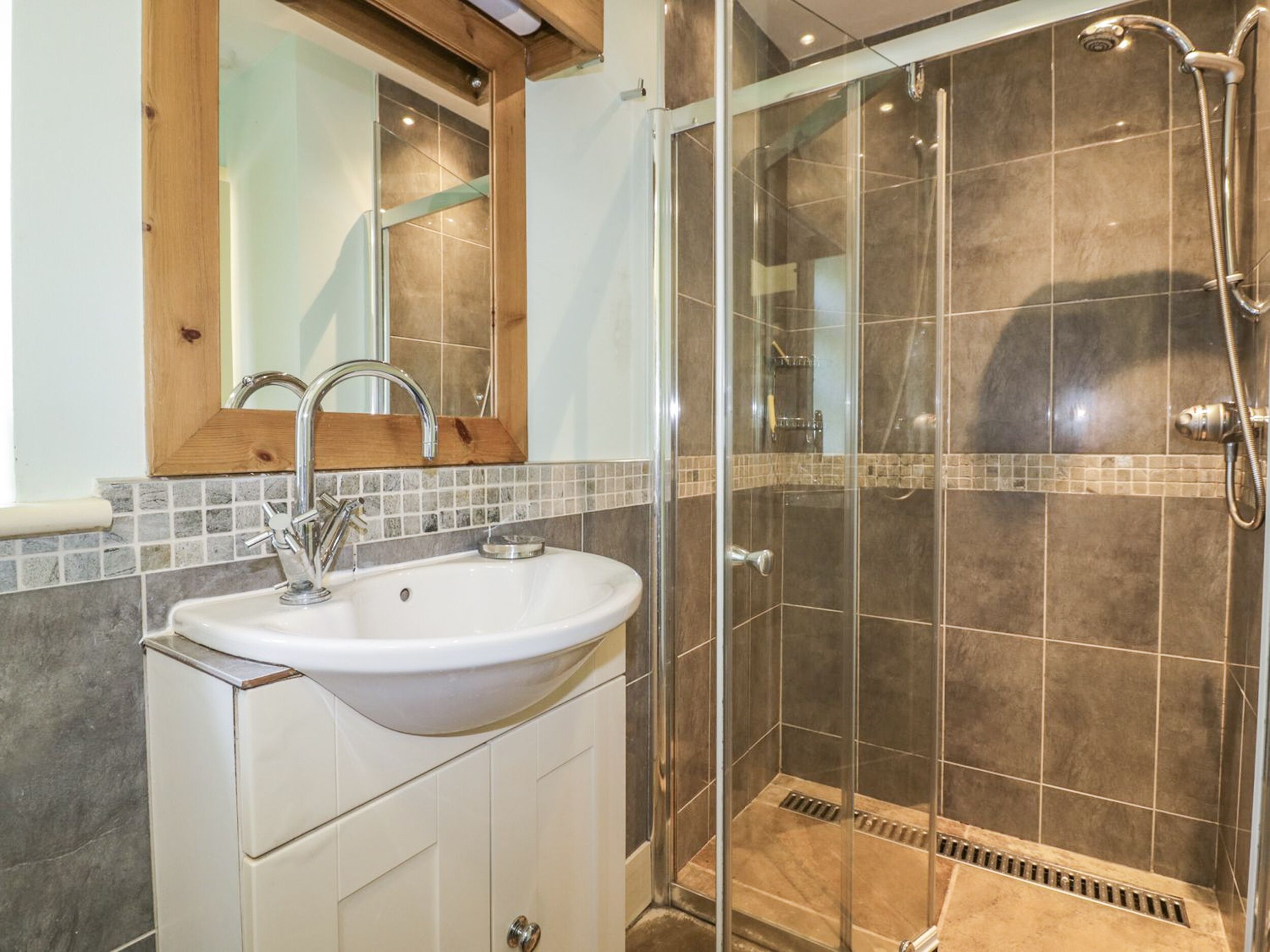 A bathroom with a sink, mirror, and shower.