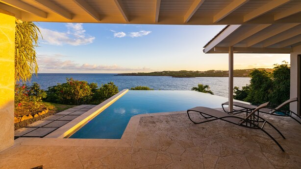 A covered infinity pool with a view of the sea, outdoor seating, and a pergola structure. - Stunning Clifftop Villa with Infinity Pool (Westerhall Land Settlement)