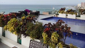 A rooftop terrace with a pool, seating area, and potted plants. - Ocean Front Suite Apartment in Manta Poseidon Building (Manta)