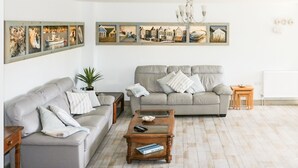 Un salon avec deux canapés gris, une table basse en bois et un lustre.