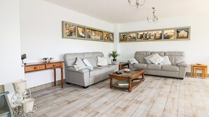 Un salon avec deux canapés gris, une table basse en bois et un tableau accroché au-dessus des canapés.