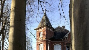 A large brick building with a tower, surrounded by trees and a grassy area. - Construction trailer - in the middle of nature (Kleve)