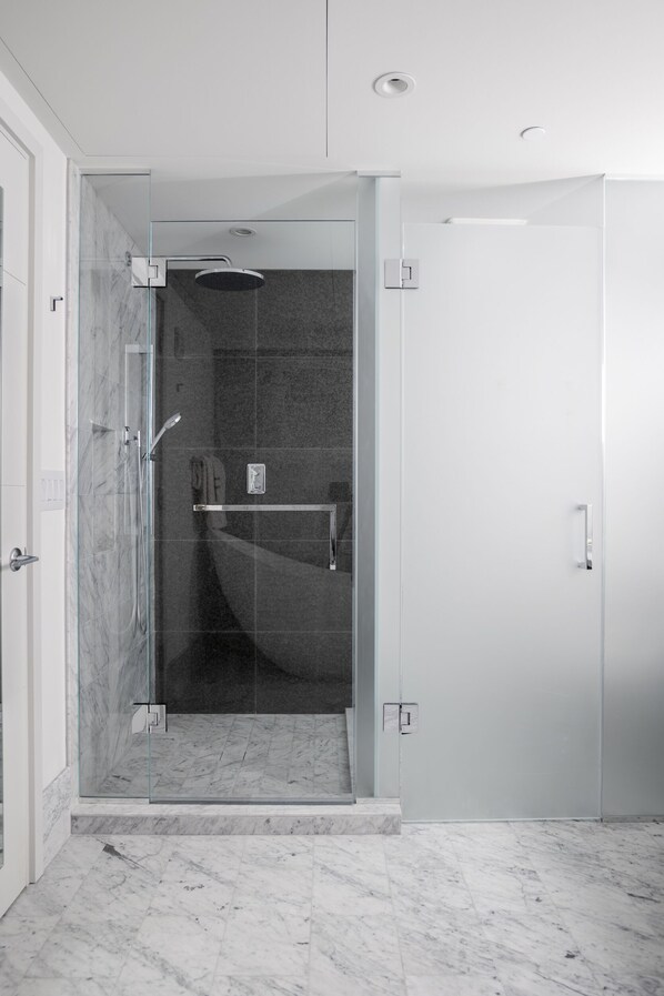 Un baño moderno con ducha de vidrio, suelo de mármol y diseño minimalista.