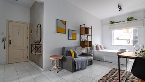 A modern living room with a grey sofa, a small round table, and a dining area with a table and chairs. - 6 Minutes From Ipanema Beach and Close to the Underground J804 (Rio de Janeiro)