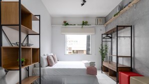 A modern bedroom with a bed, shelves, a desk, and a red bench. - 6 Minutes From Ipanema Beach and Close to the Underground J804 (Rio de Janeiro)
