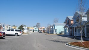 A residential street with colorful houses, a parking lot, and a clear blue sky. - 2-Bedroom Cottage, One Block to Beach! Free WIFI, Free Parking (Myrtle Beach)