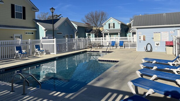 A swimming pool with lounge chairs and a white fence. - 2-Bedroom Cottage, One Block to Beach! Free WIFI, Free Parking (Myrtle Beach)