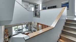 Un interno moderno con una scala che conduce a un livello inferiore, un angolo cottura e un'area pranzo con vista.