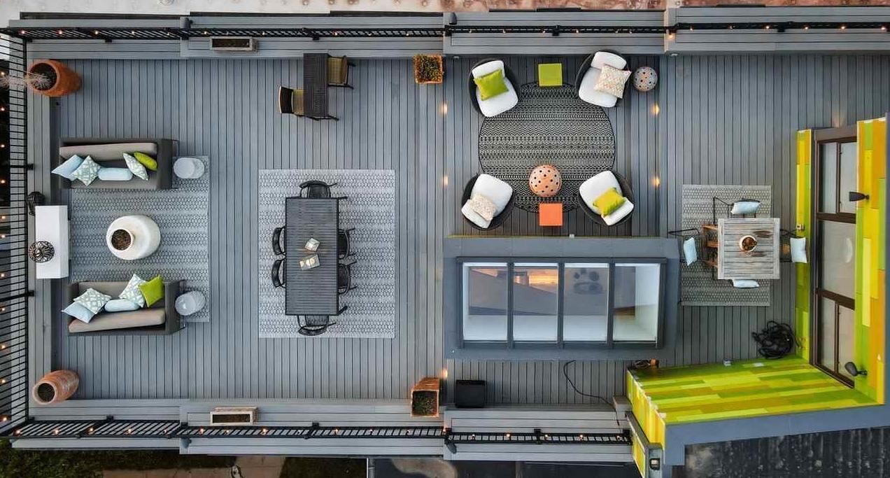 A spacious outdoor deck with multiple seating areas, including a dining table and chairs, a sofa set, and a small table with chairs.