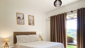 Ein Schlafzimmer mit einem Bett, Nachttischen und Blick ins Freie.