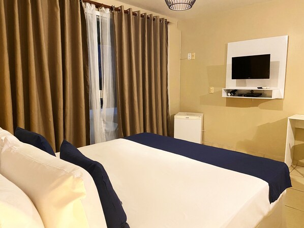 A hotel room with two beds, a TV, a small white cabinet, and a window with curtains. - Villa Casablanca (Búzios)