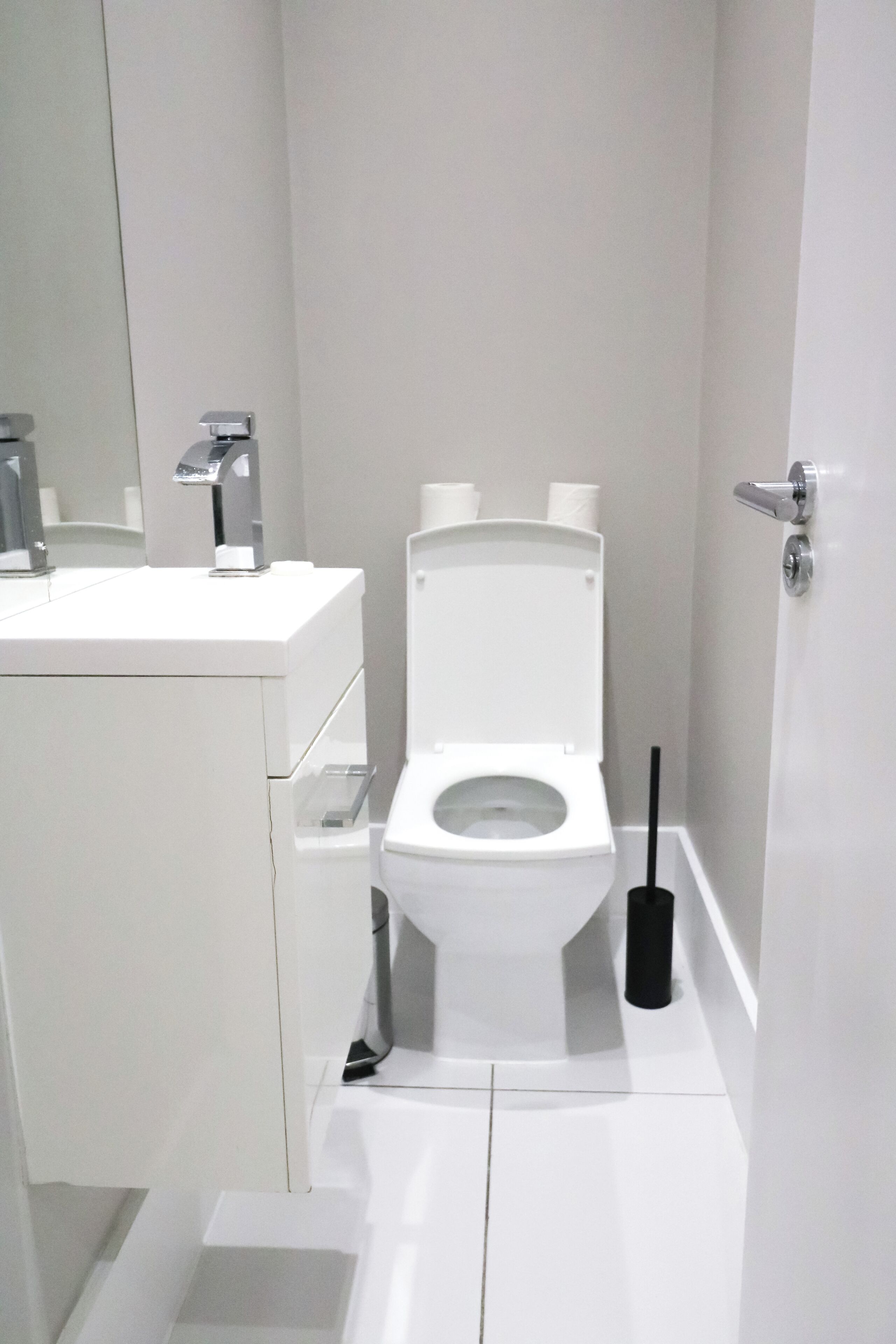 Uma casa de banho moderna com sanita branca, lavatório e espelho.